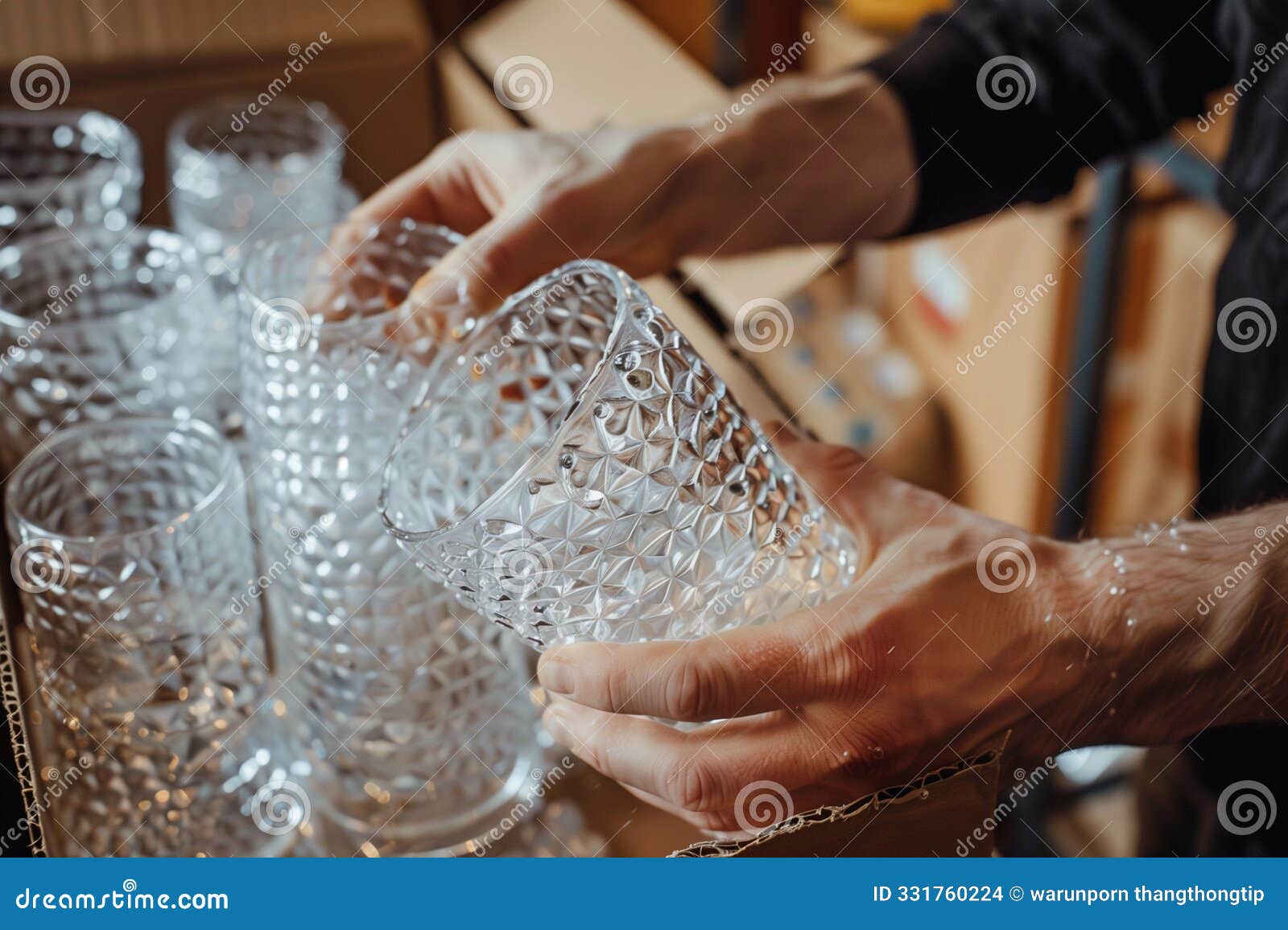 hands carefully wrapping fragile glassware with plastic bubble put in cardboard. home decoration package