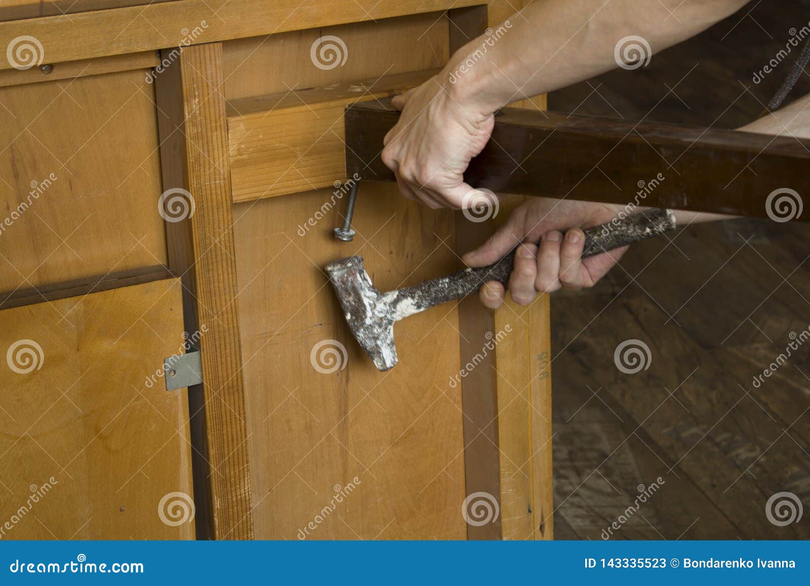 The Hands Of A Carpenter Restoring Old Furniture With Hammer