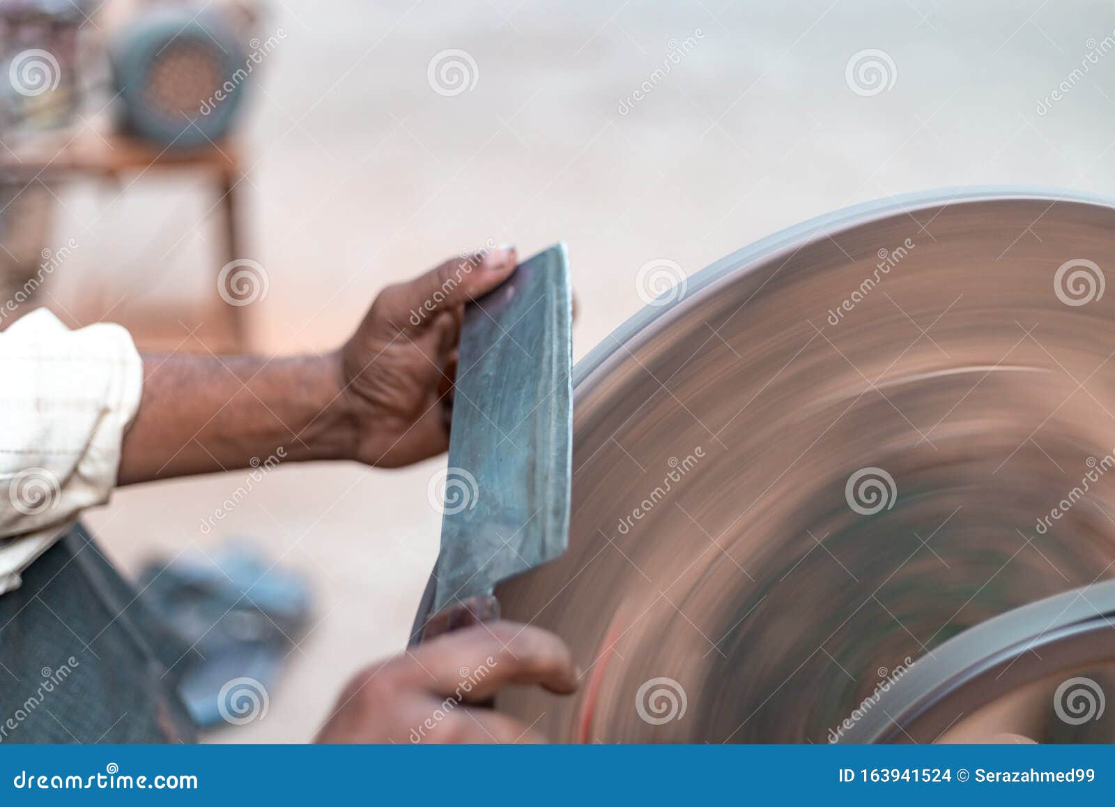Hands of Construction Worker Sharpens a Knife on Sanding Machine Stock