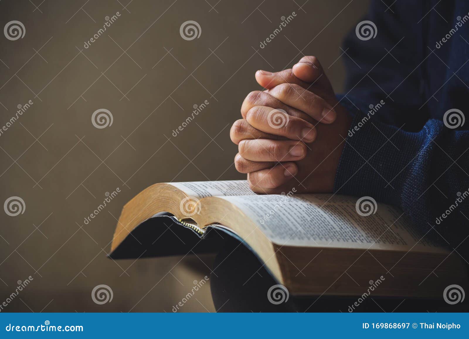 hands folded in prayer on a holy bible in church concept for faith