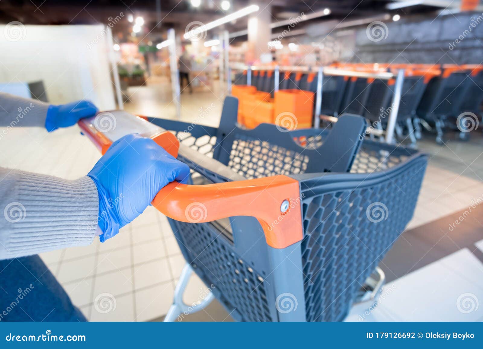 hands in glives with a shopping cart at a supermarket.