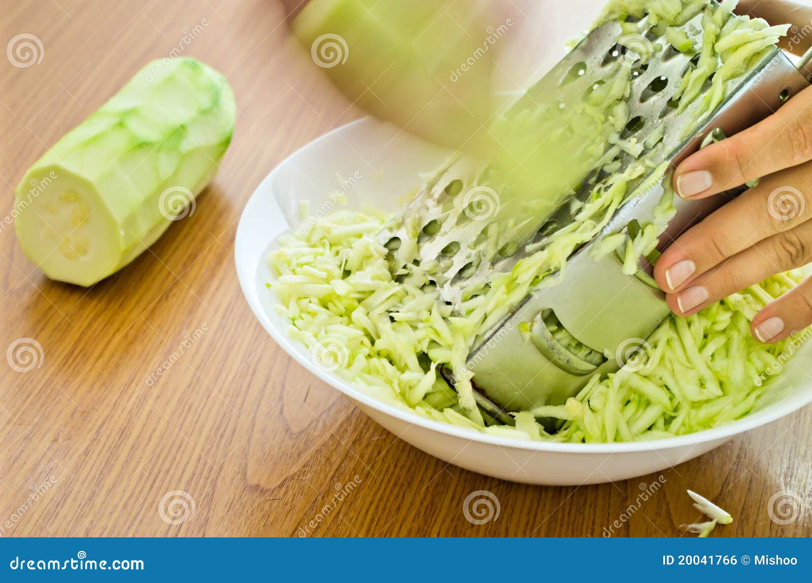 hands grating zucchini