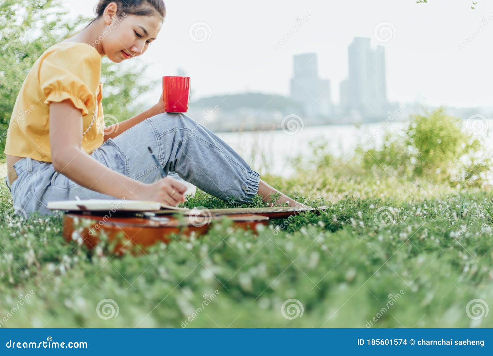 hands hold coffee cup and write notes,lyrics in the book on quitar beside the sea and building city background