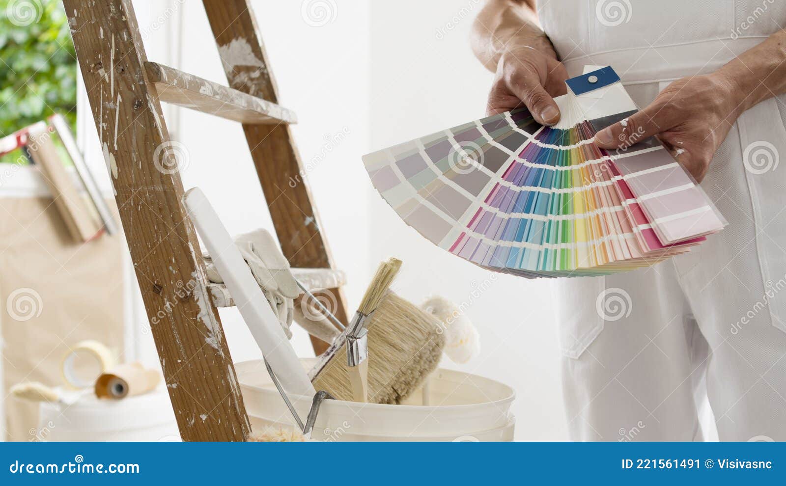 hands of house painter man decorator choose the color using the sample swatch, work of the house to renovate, a wooden ladder with