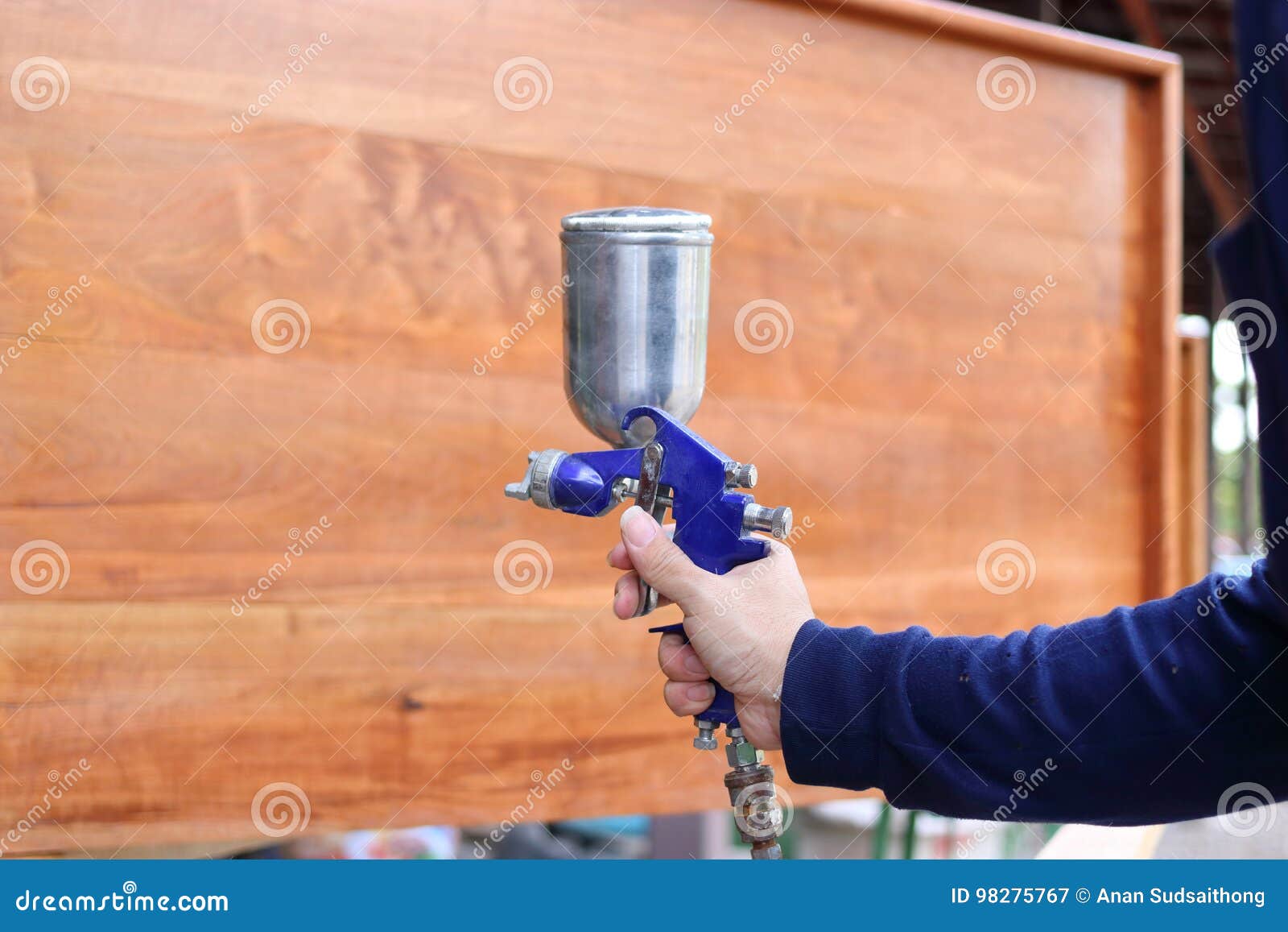 Hands Of Industrial Worker Applying Spray Paint Gun With A Wooden