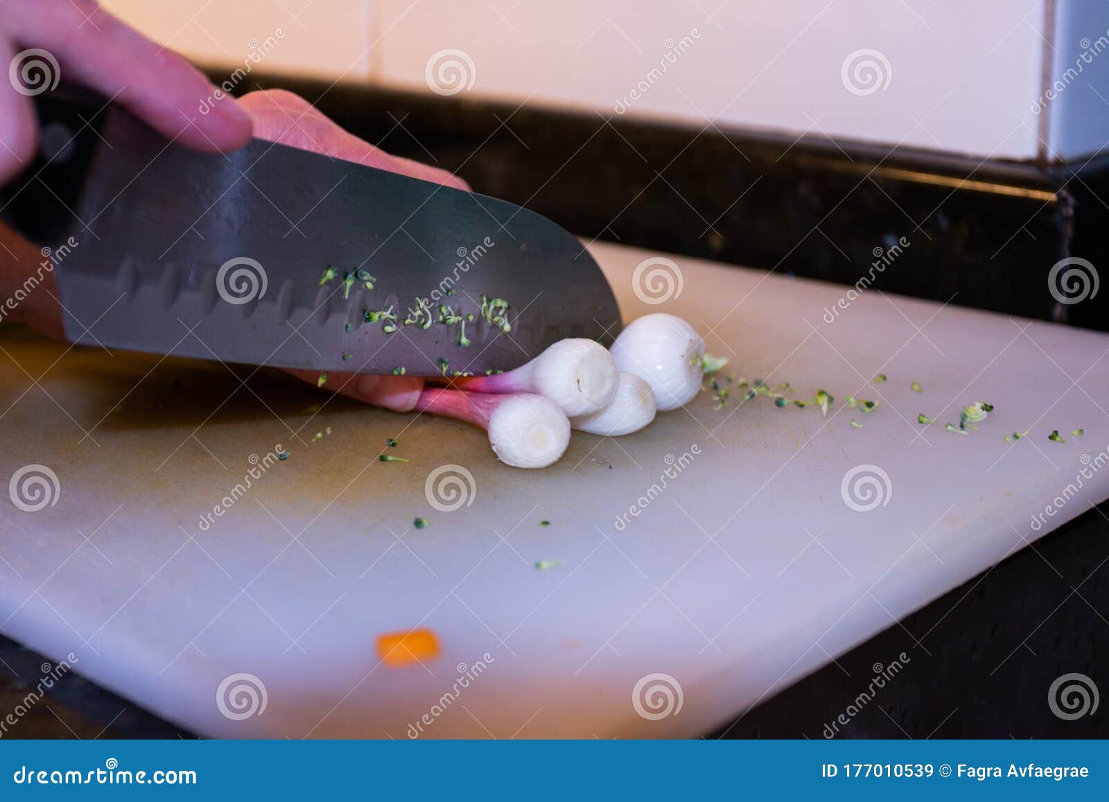 Hands with Kitchen Knife Cutting Vegetables on the White Table in the