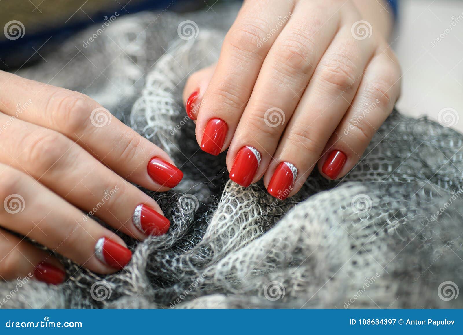 Hands with Long Artificial Manicured Nails Colored with Red Nail Polish