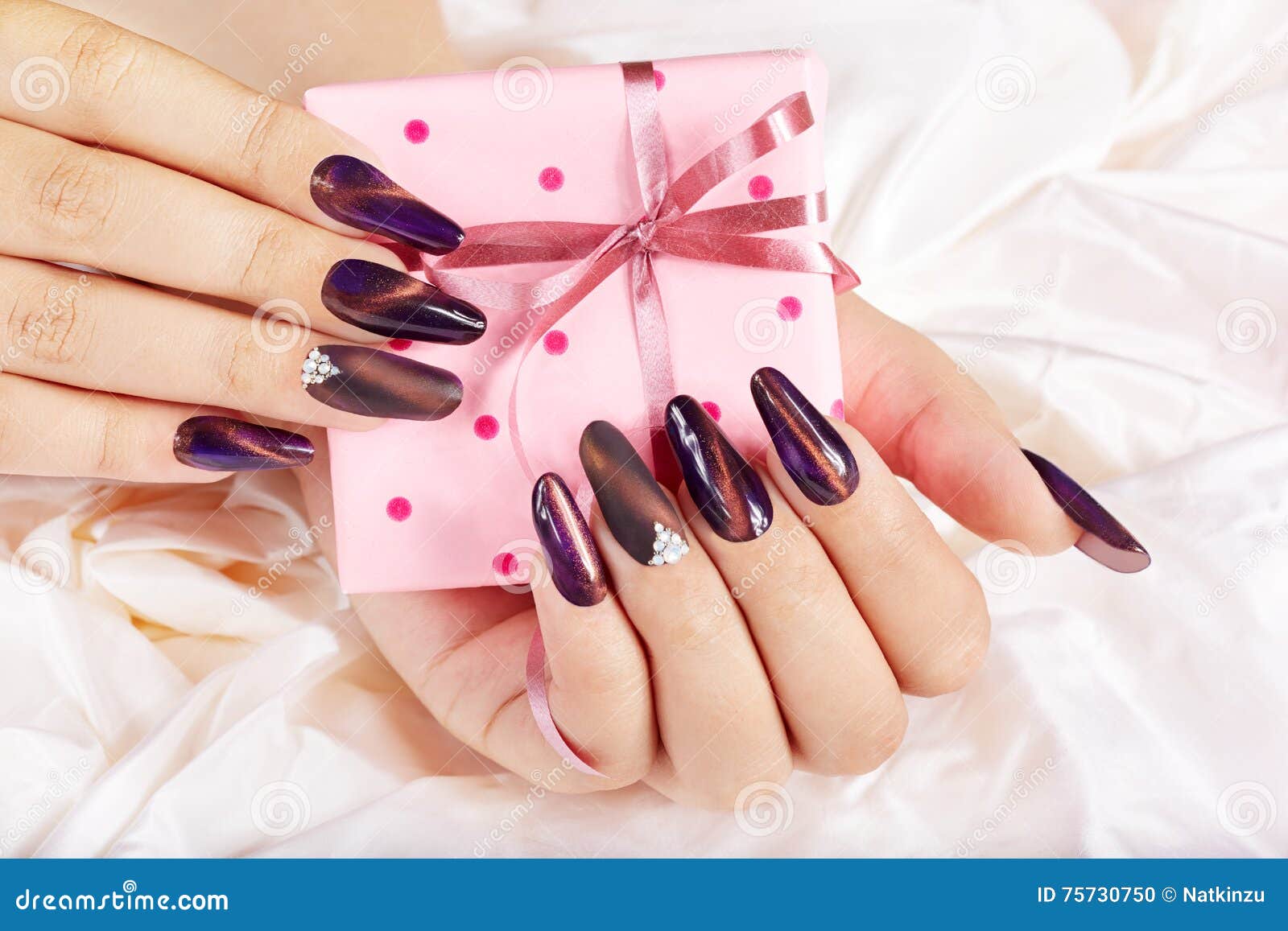 hands with long artificial manicured nails holding a gift box