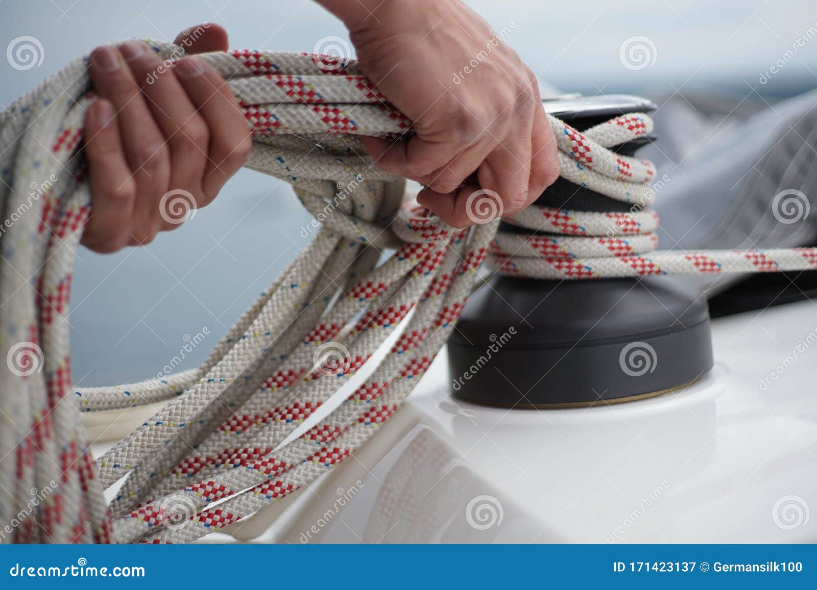 hands of a man coiling up a rope, the halyard on a sailboat