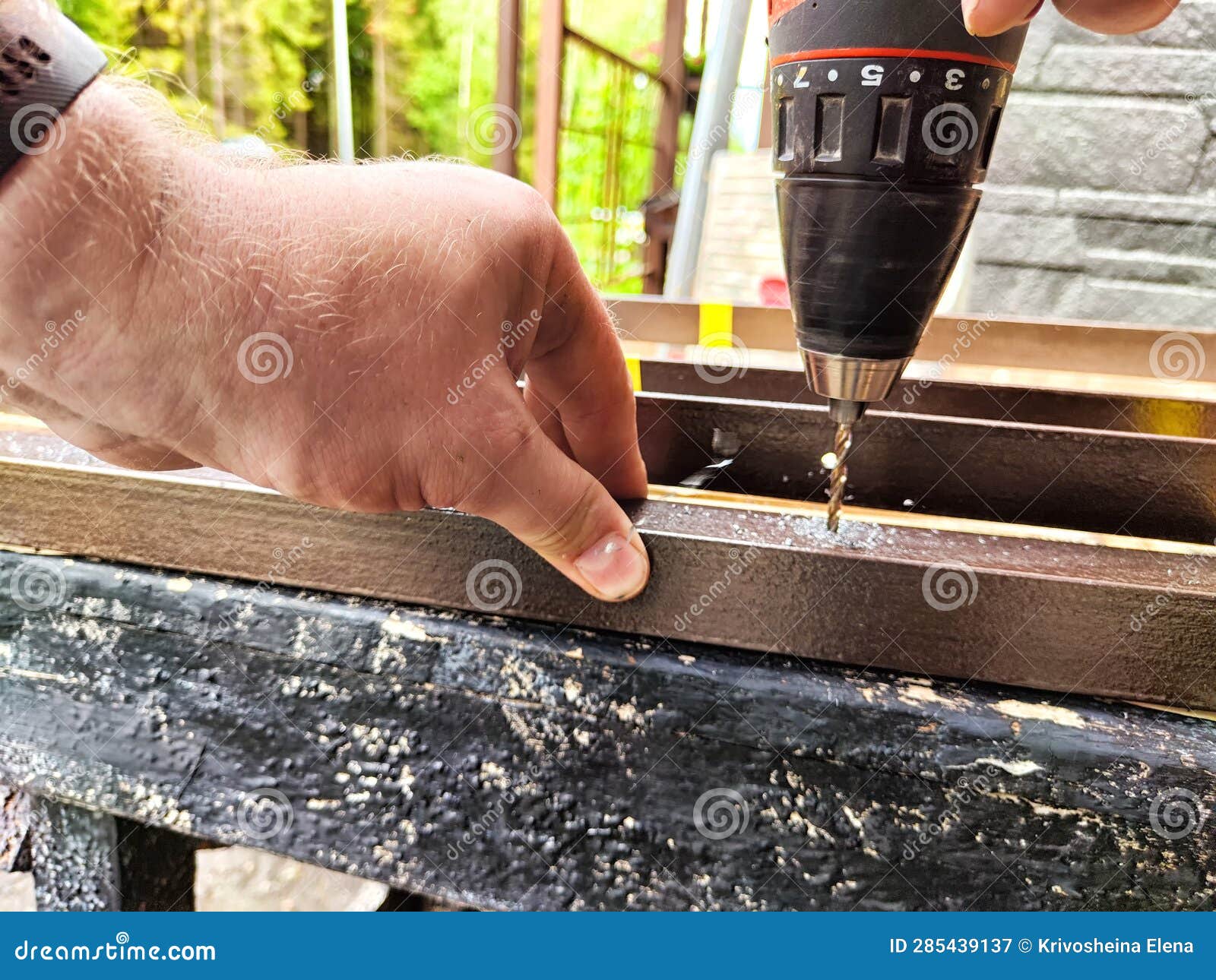 The Hands of a Man and Screwdriver that Drills Metal Bars. Drill Bit