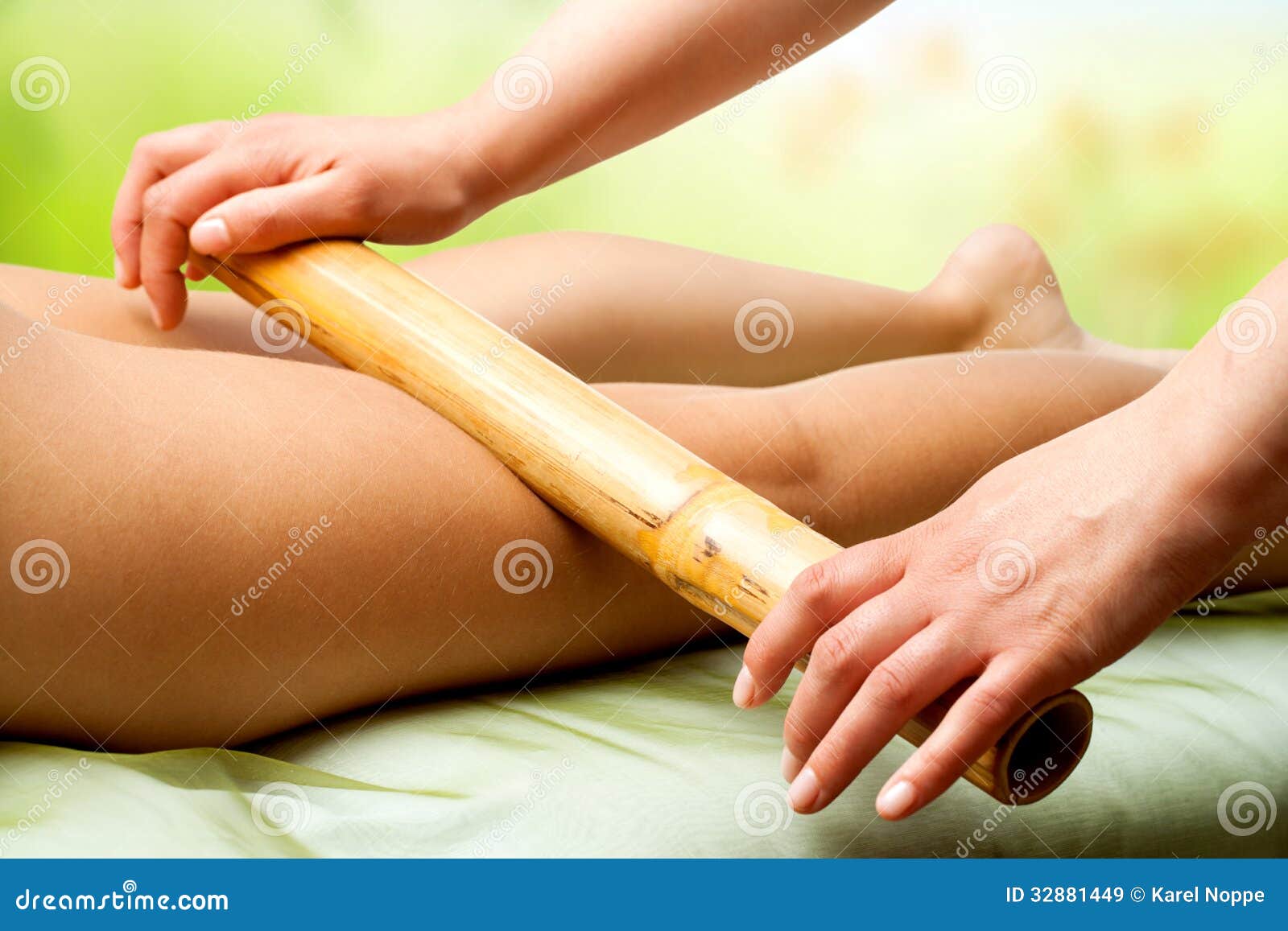 hands massaging female legs with bamboo.