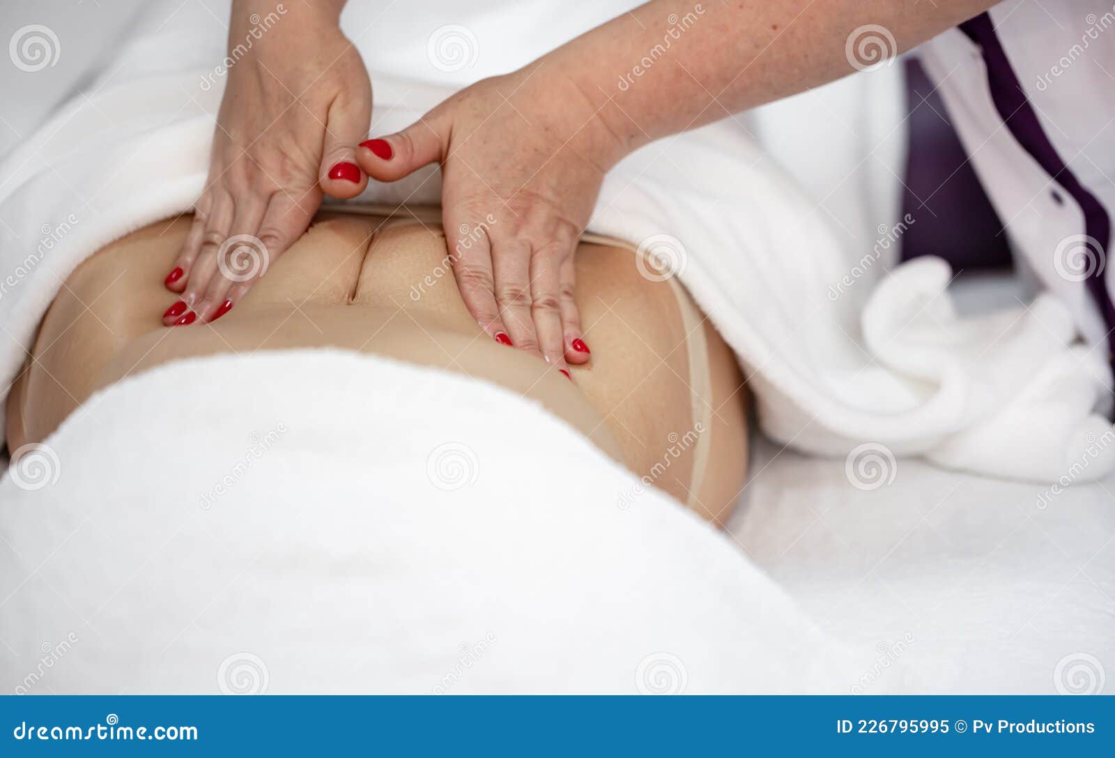 Hands of female therapist giving back massage to woman relaxing on