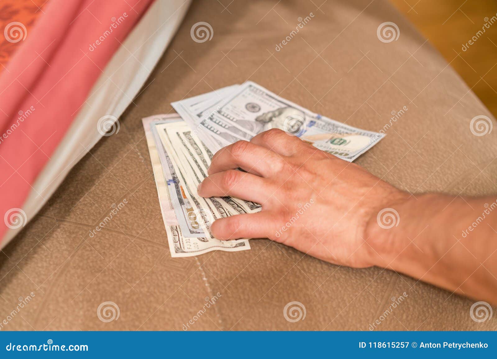 hands with money hide them under mattress. a man's hand takes money from under the pillow. a man hides money in a bed