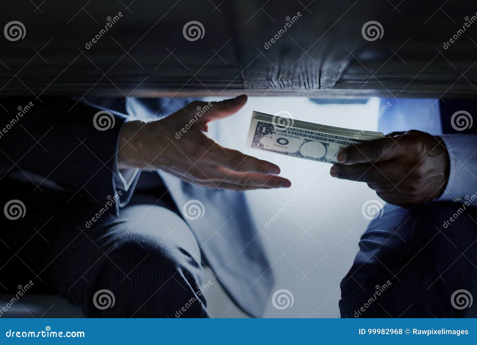 hands passing money under table corruption bribery
