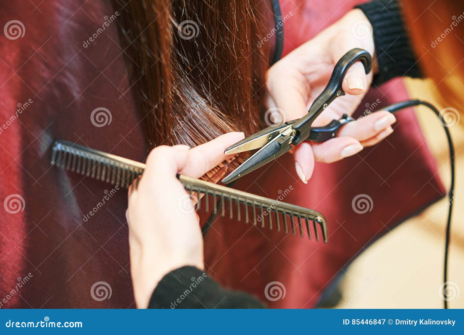 hands of professional hair stylist with scissors and comb