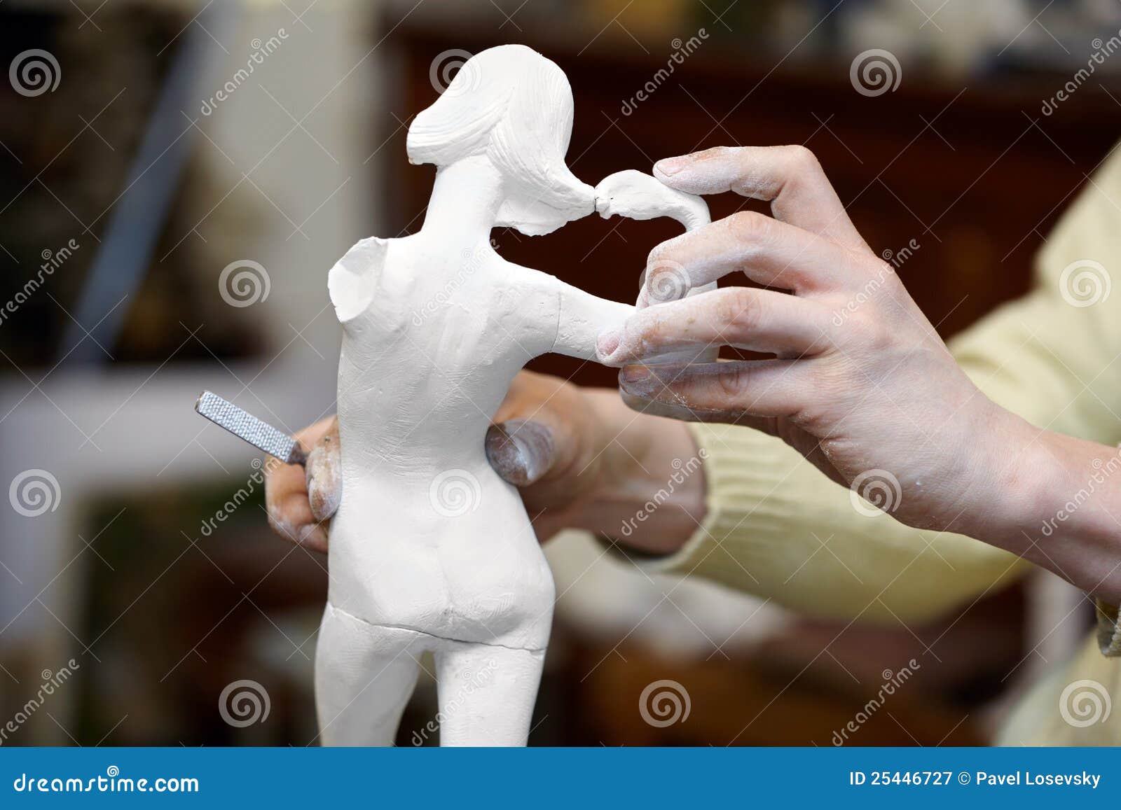 hands of sculptor works with statuette.