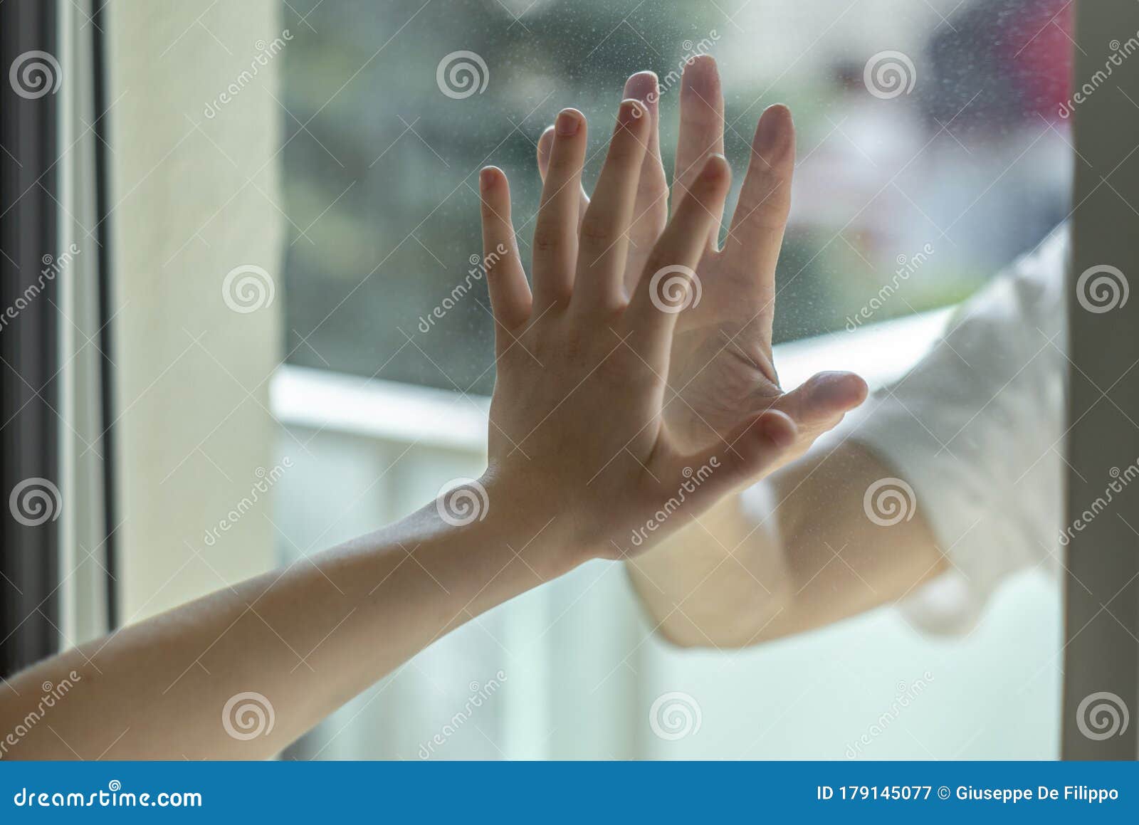 hands separated by a glass window for social distancing during the corona virus lockdown