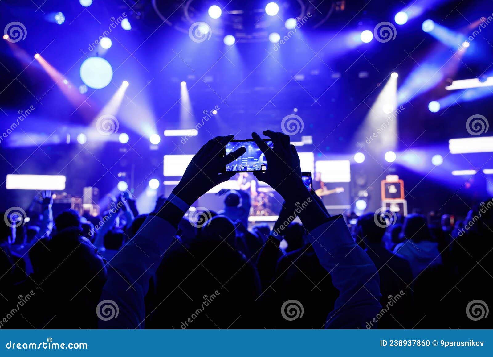 Hands with a Smartphone at the Concert Hall during Music and Light Show