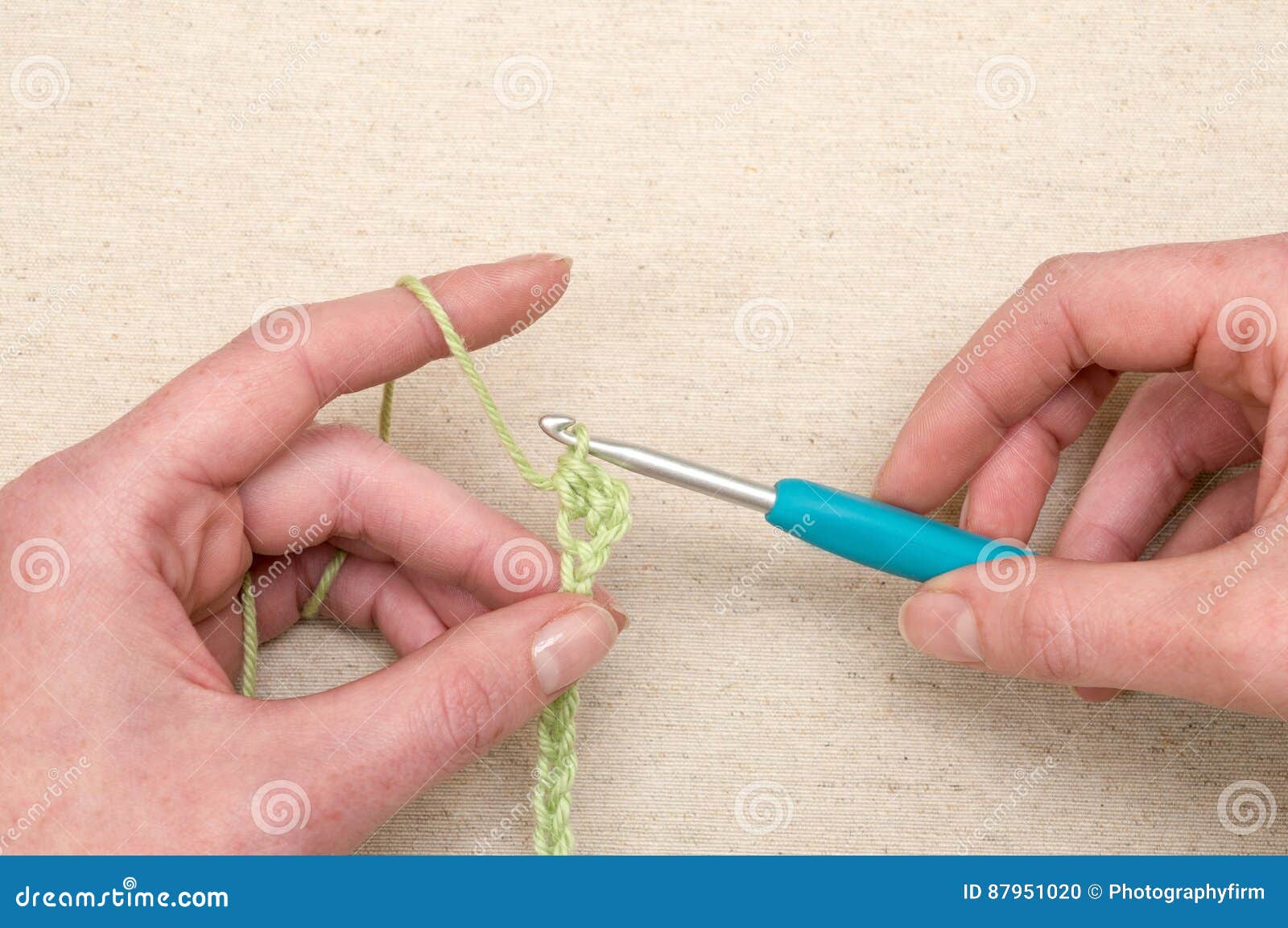 Hands Stitching a Chain of Green Yarn Using Knitting Hook Stock Photo