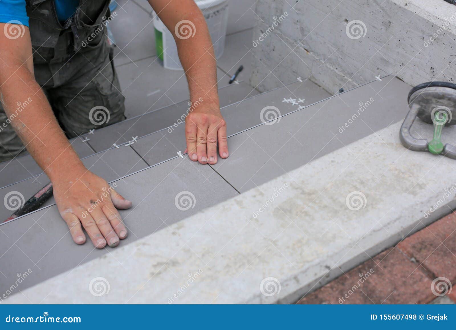 The Hands Of The Tiler Are Laying The Ceramic Tile On The Floor