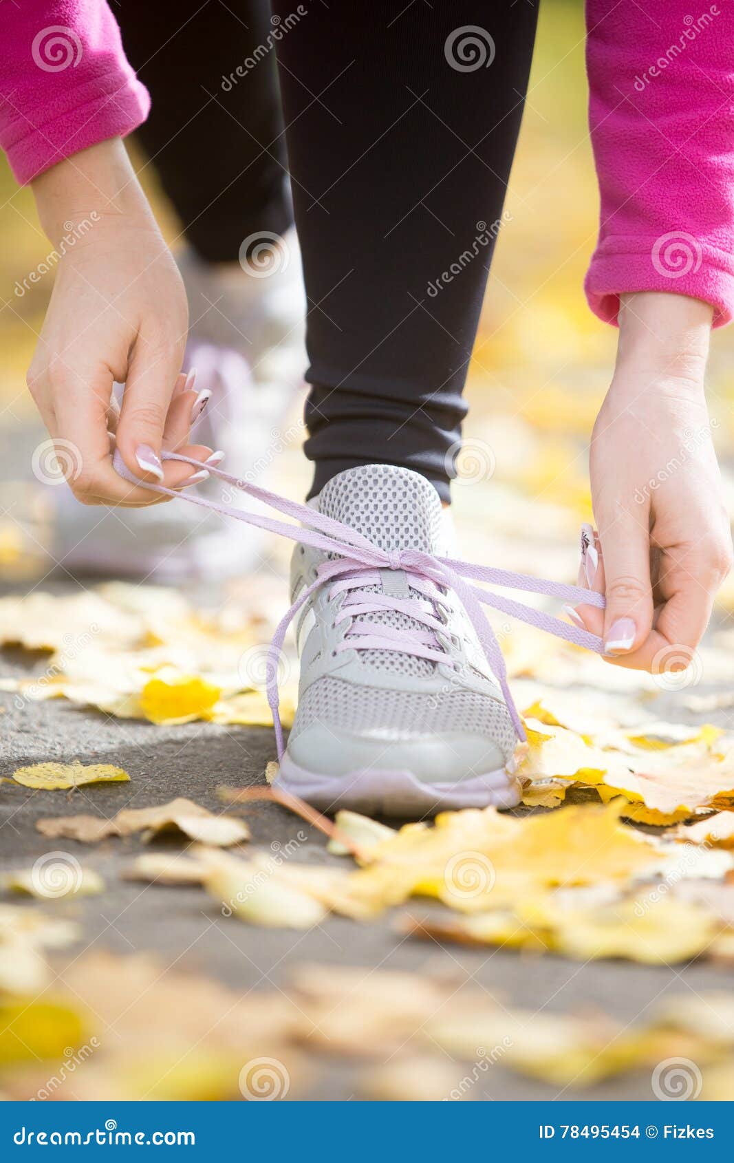 hands tying trainers shoelaces on the fall pave