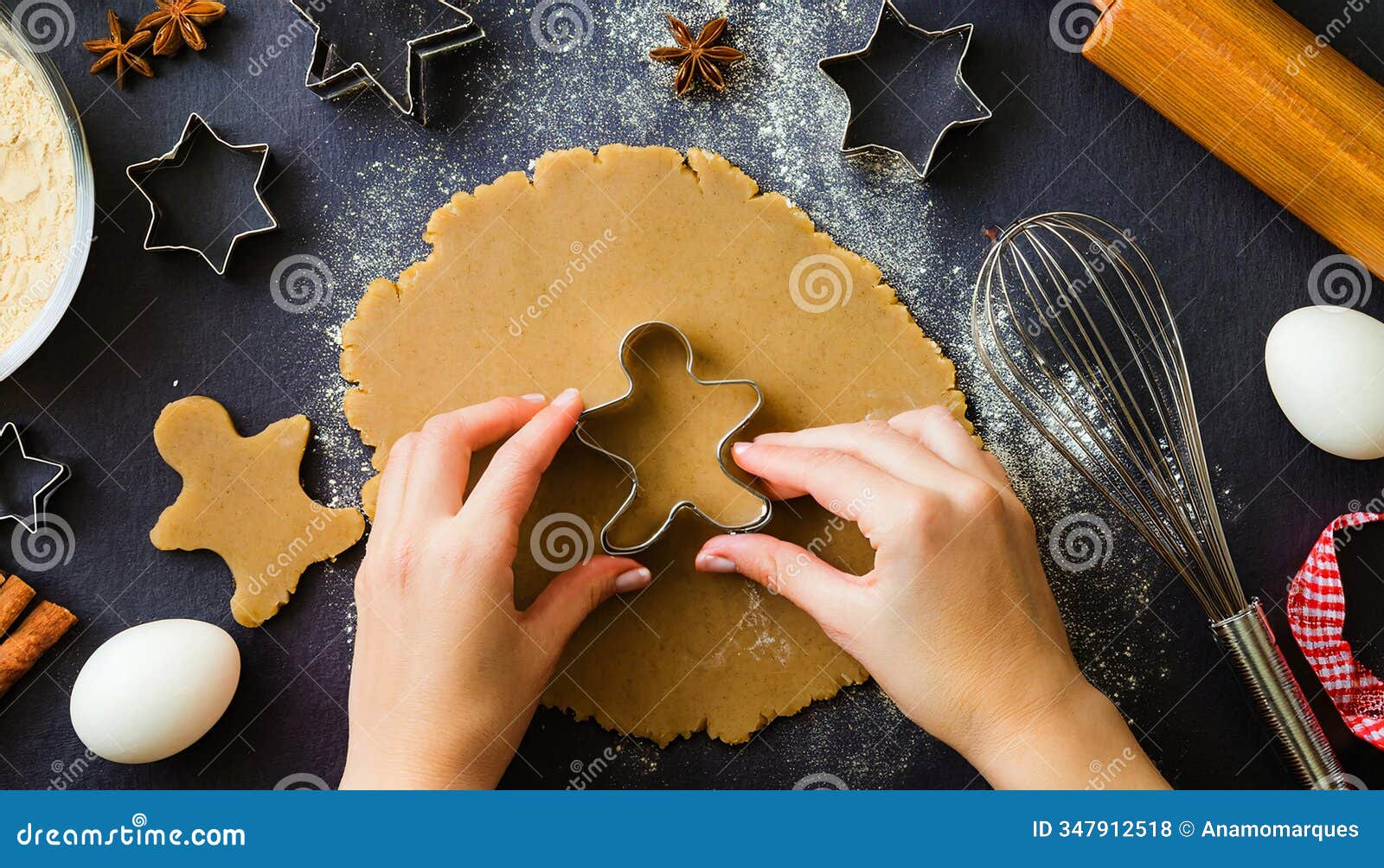 hands using a gingerbread man cookie cutter on rolled-out dough, surrounded by baking tools and ingredients, creating festive
