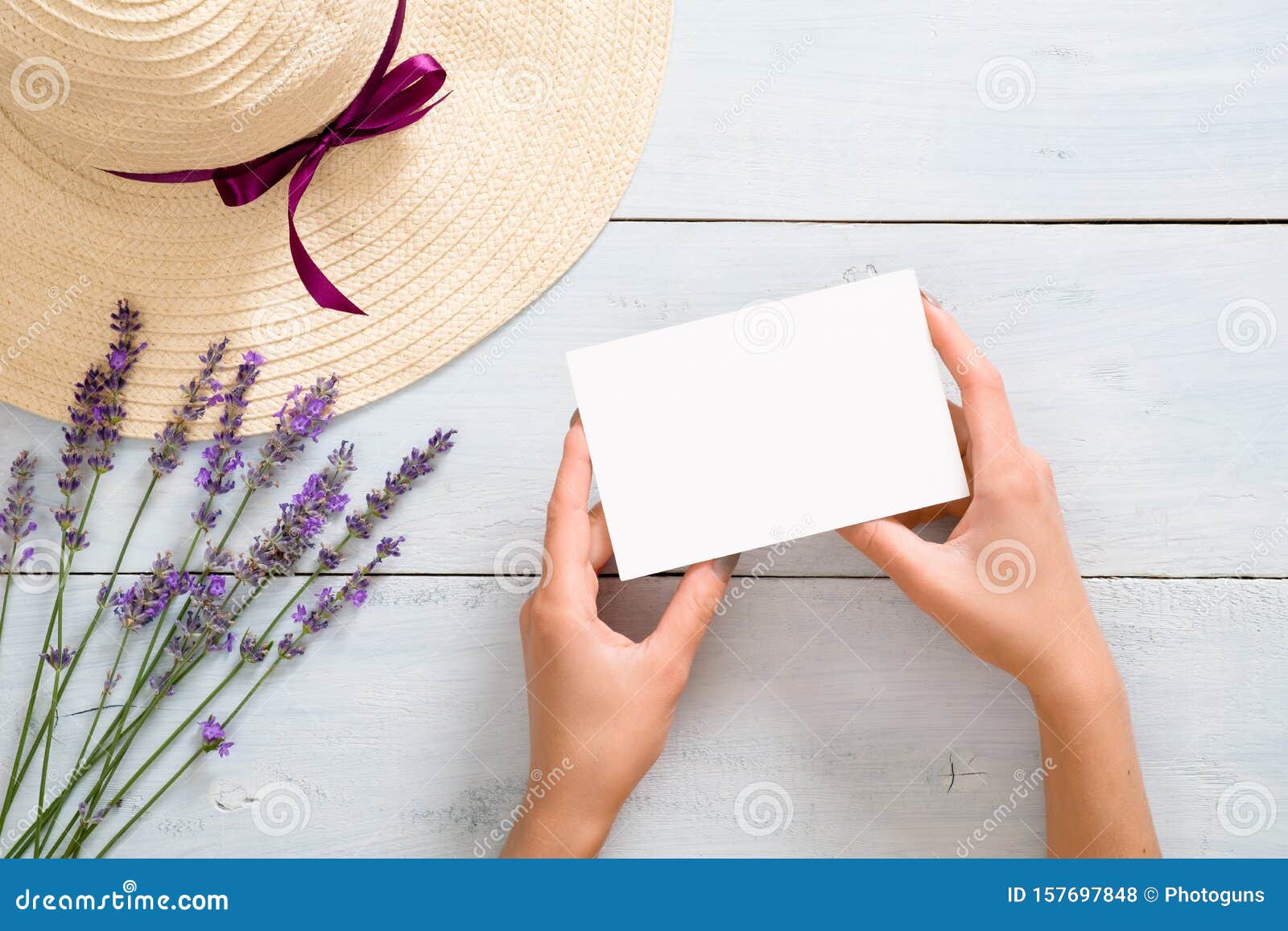 Download Hands Of Woman Holding Blank Paper Card Mockup Over Rustic Blue Wooden Background With Straw Hat ...