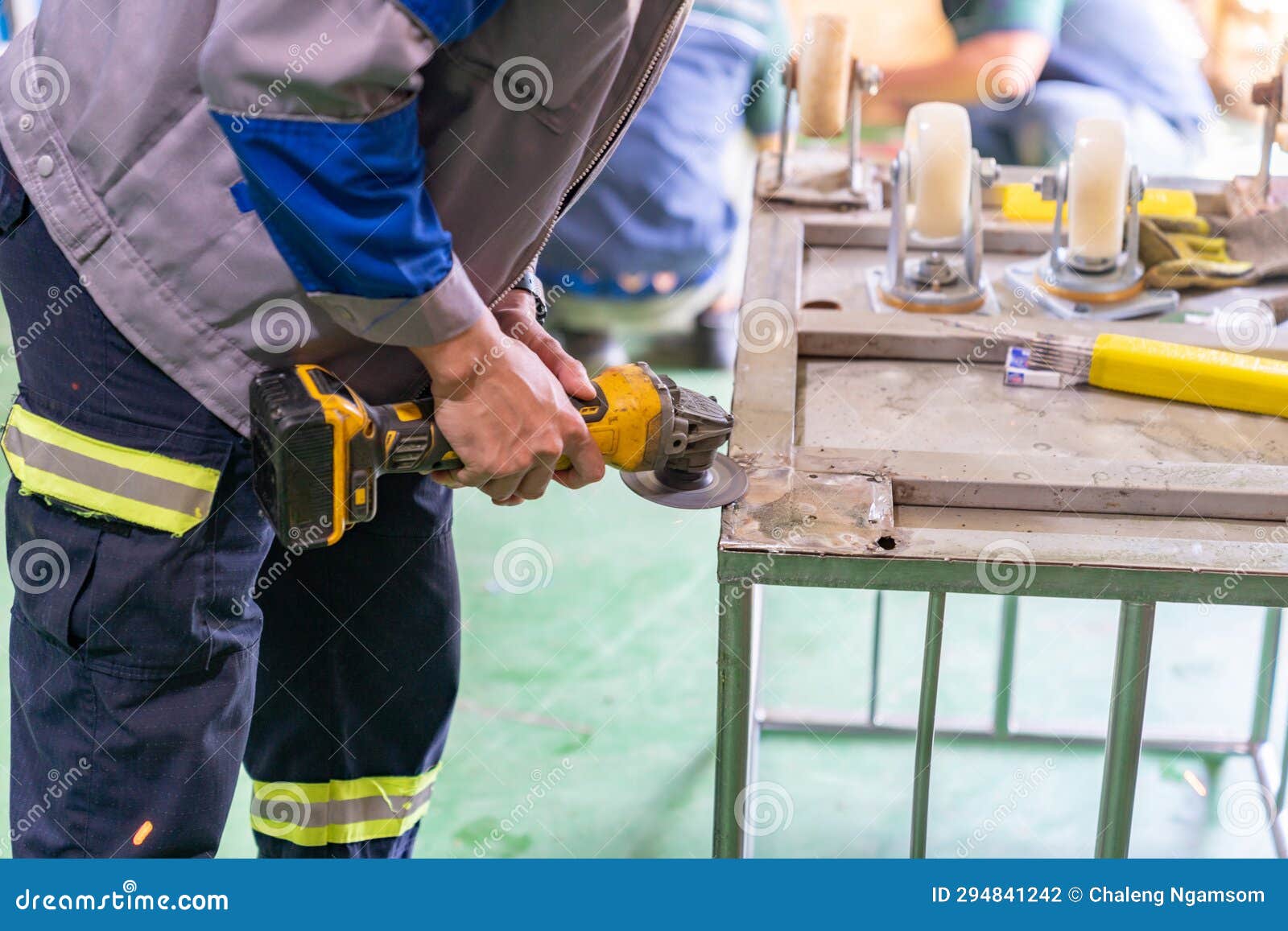 Hands of Worker Grinding a Cart Base Wheel for Install Stock Photo