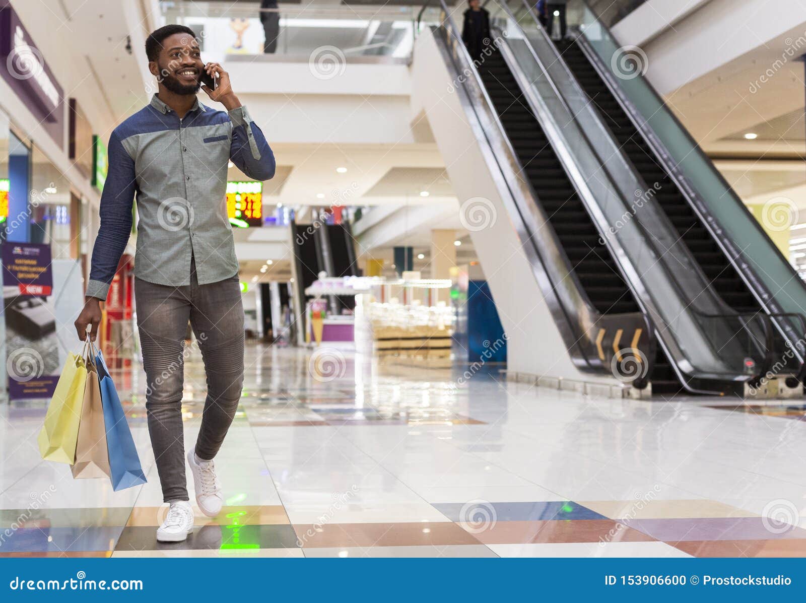 handsome african man with shopping bags talking by cellphone