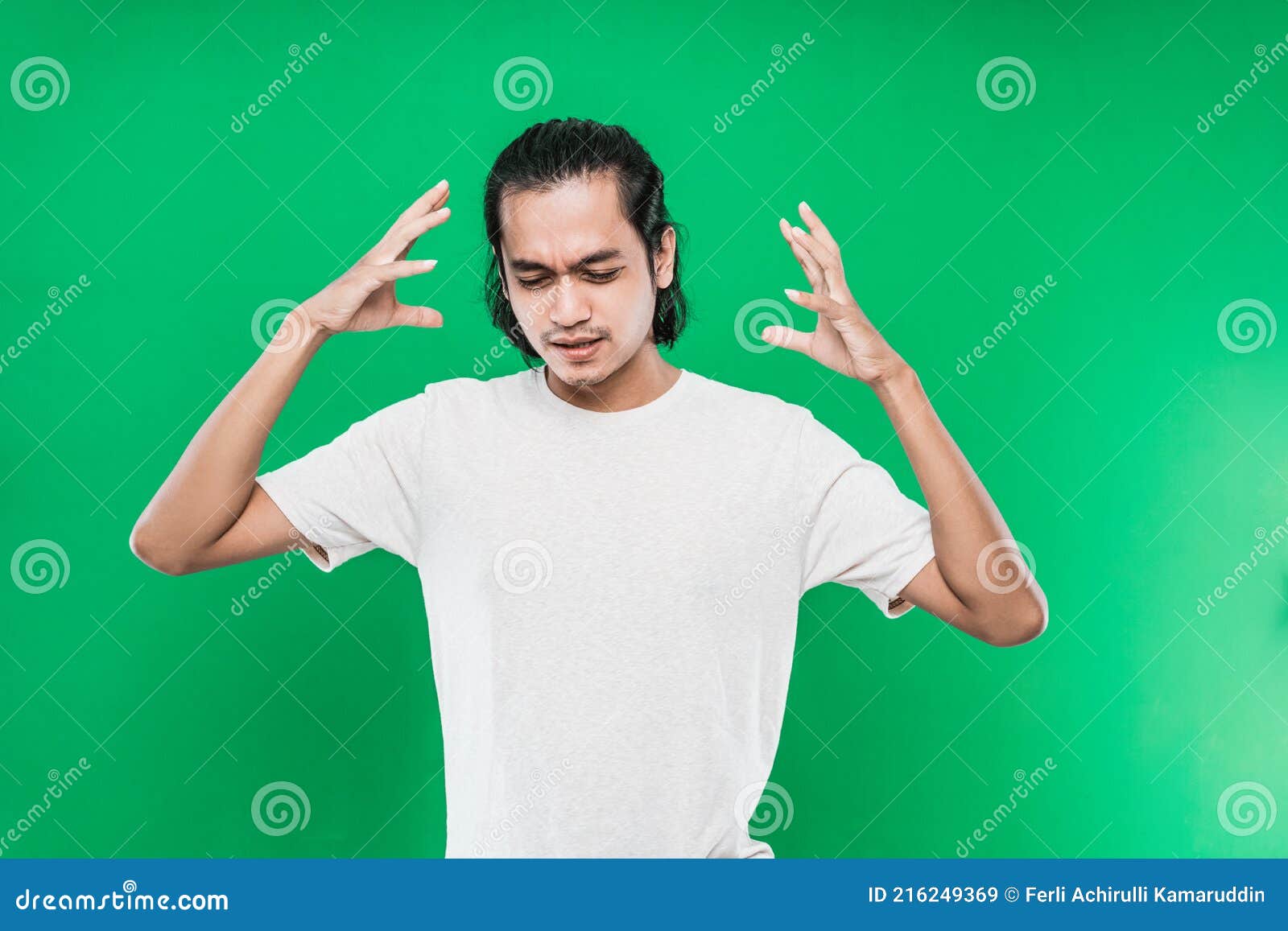 handsome asian man with a flustered expression on the face while raising two hands at the side of the head