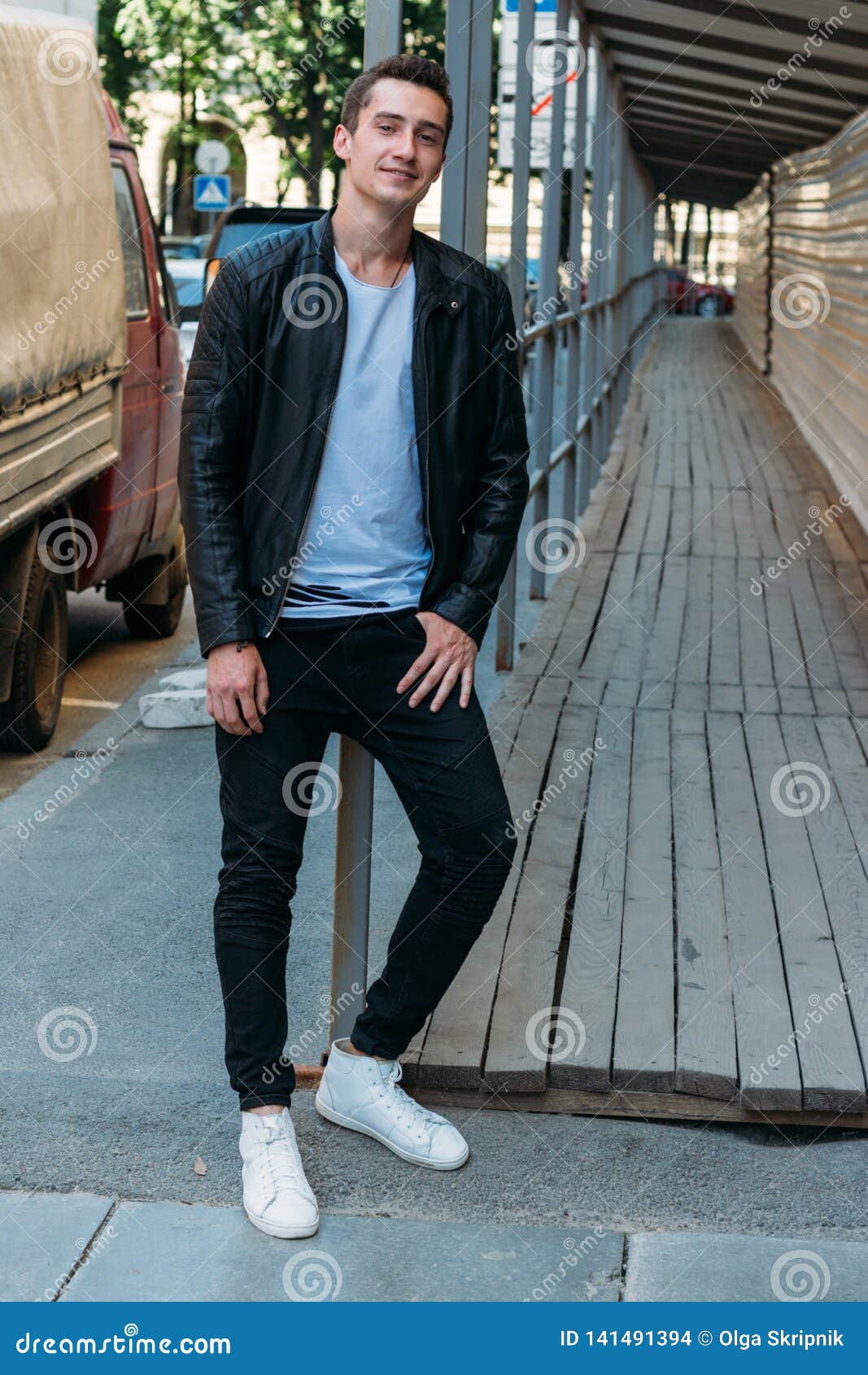 Handsome, Attractive Guy, Standing Leaning On The Railing In A White T-Shirt,  Black, Leather Jacket, Black Pants And White Stock Photo - Image Of  Beautiful, Pants: 141491394