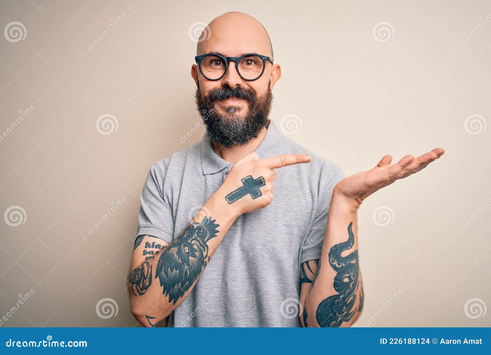 Handsome Bald Man with Beard and Tattoo Wearing Casual Polo and Glasses Amazed and Smiling To the Camera while Presenting with Stock Photo - Image of polo, background: 226188124 Handsome Bald Man with Beard and Tattoo Wearing Casual Polo and Glasses Amazed and Smiling To the Camera while Presenting with Stock Photo - Image of polo, background: 226188124