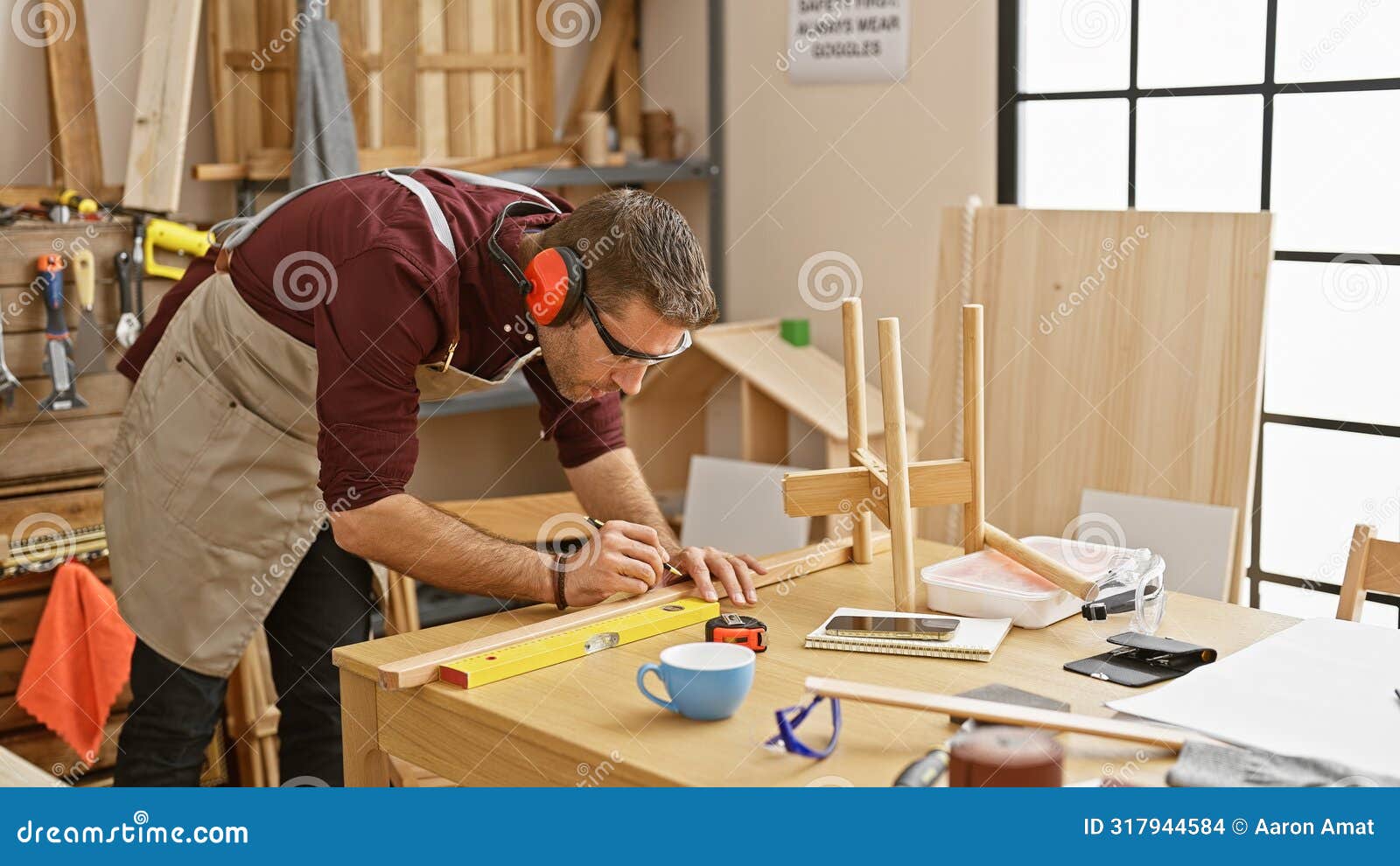 handsome bearded craftsman using tools in a well-organized woodworking workshop