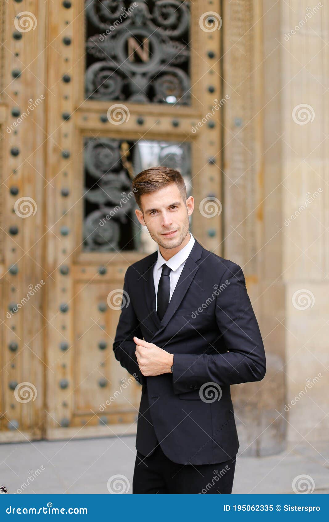 handsome cauasian groom standing near wooden door.