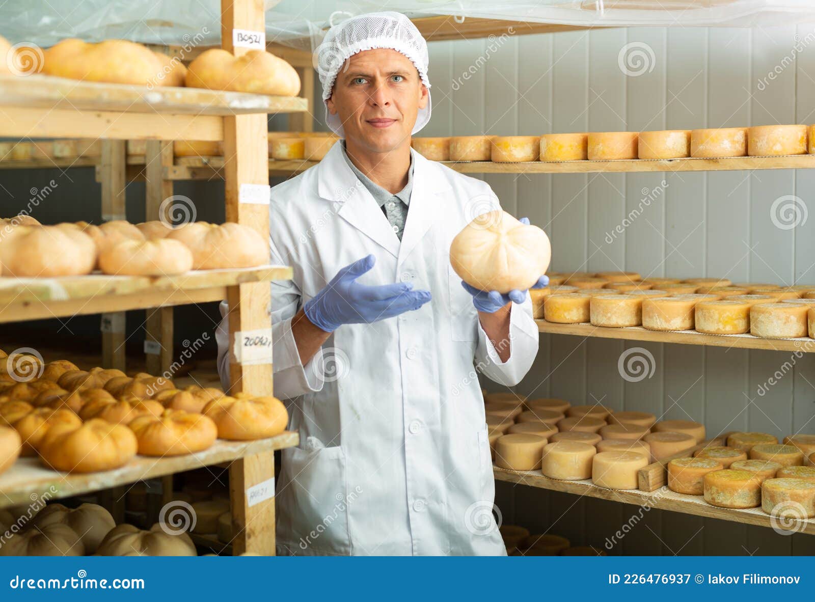 Handsome Cheese Maker Checking Aging Process of Goat Cheese Standing at