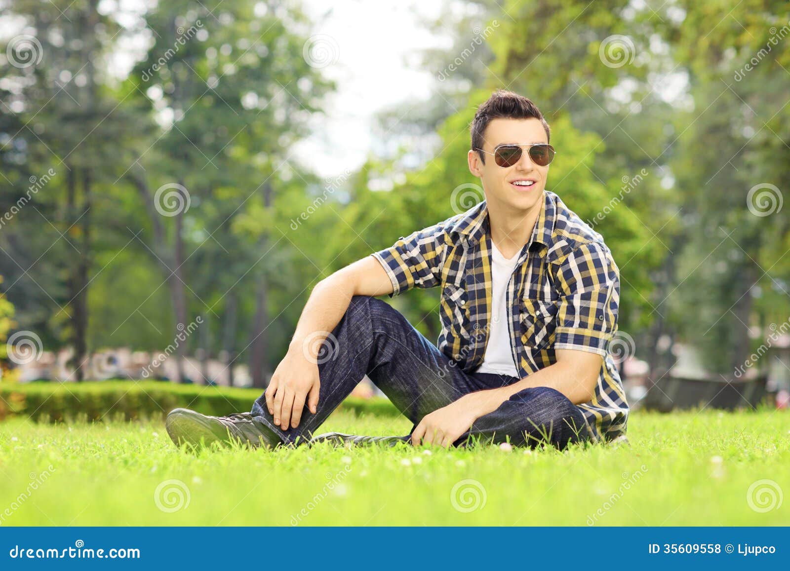 handsome guy sunglasses sitting grass looking cam green camera park 35609558
