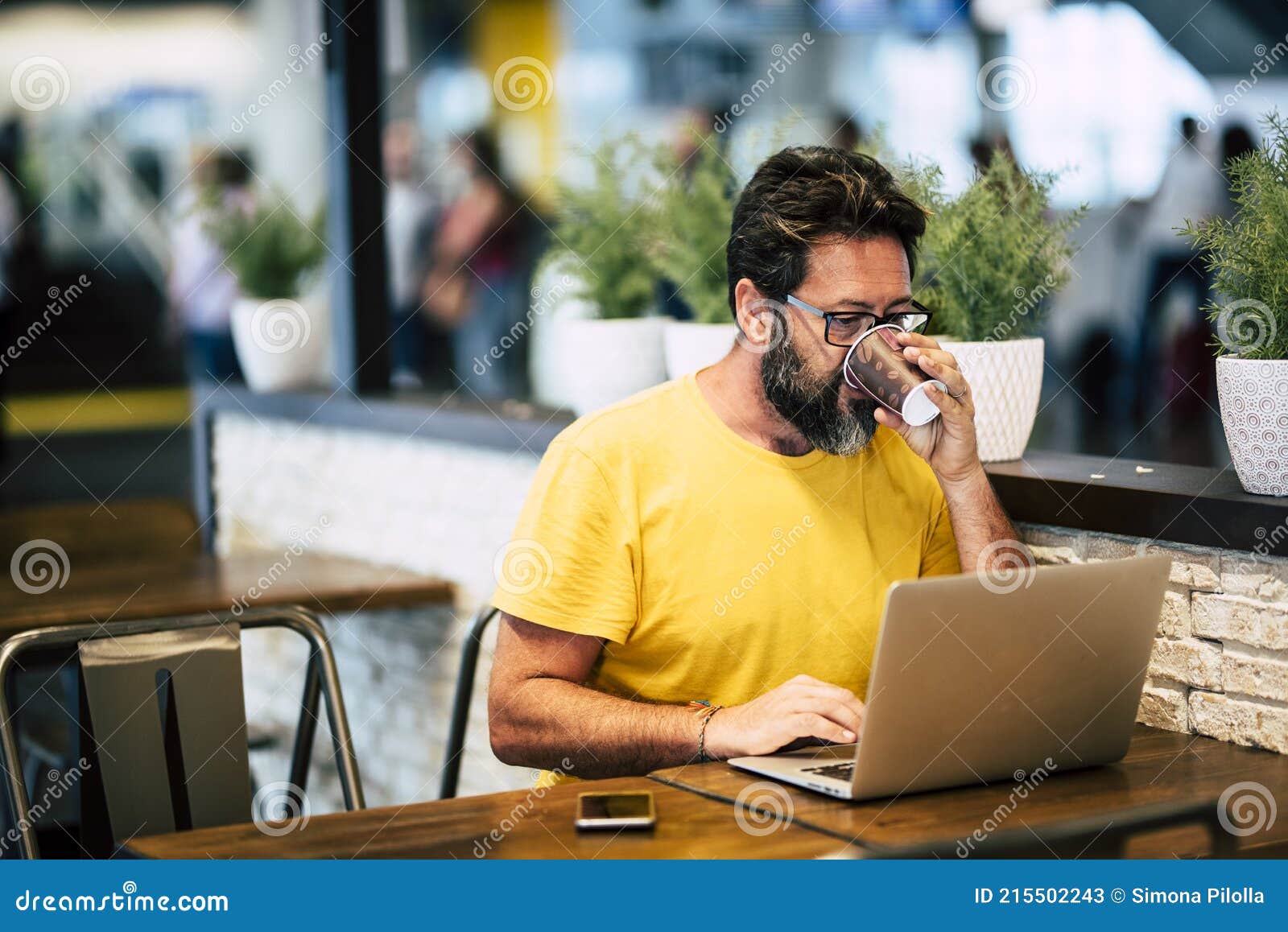 handsome hipster bearded man drink coffee at the coworking space and work with laptop computer and internet free wifi connection