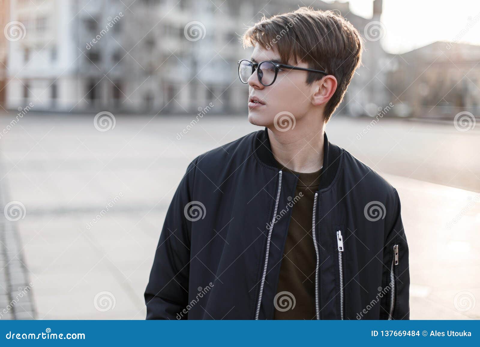 Premium Photo  Urban young man hipster in oversize leather jacket in  vintage jeans with hairstyle walks on the street near the parking lot  american guy in trendy clothes outdoors casual fashion