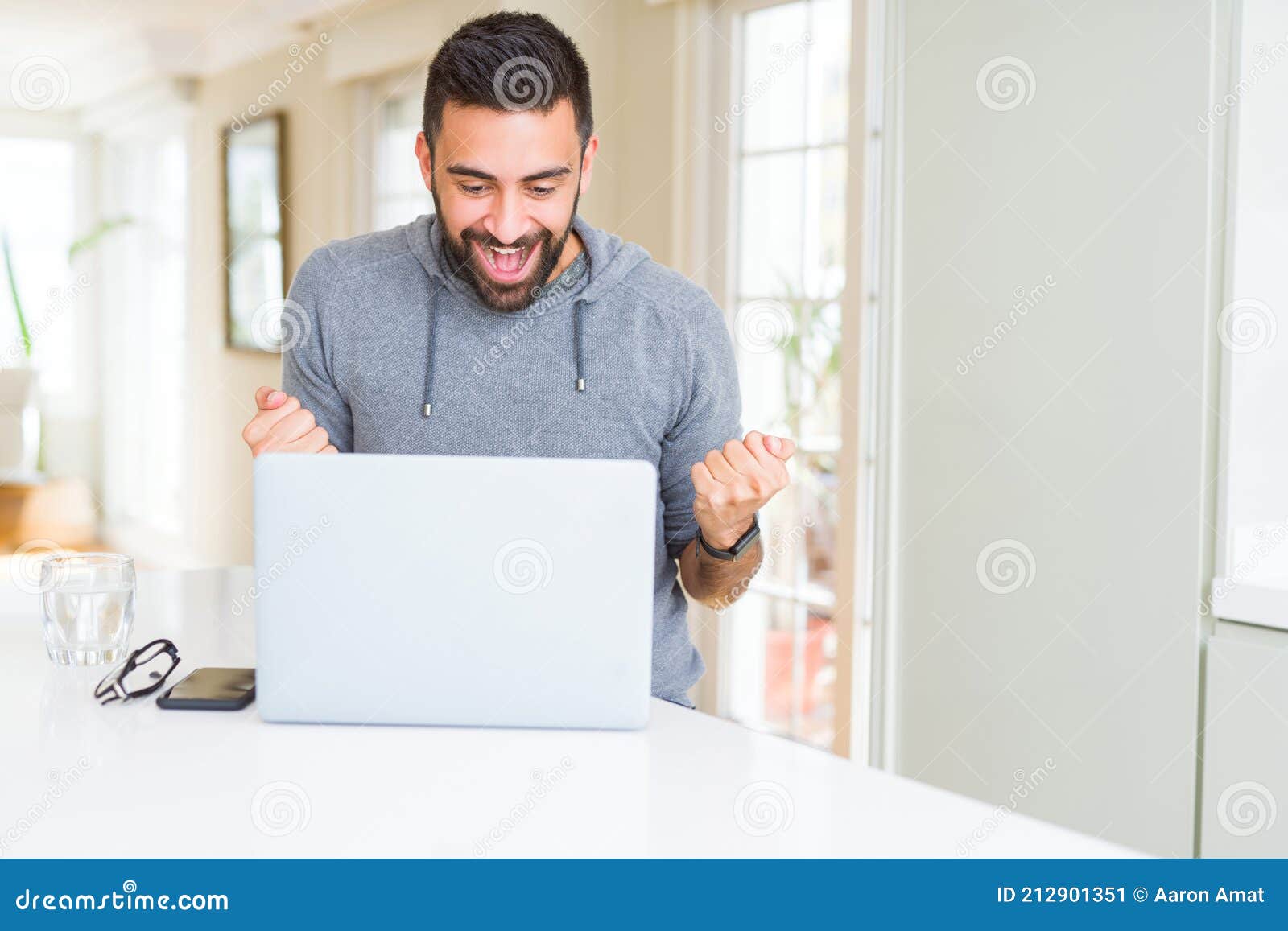 handsome hispanic man working using computer laptop screaming proud and celebrating victory and success very excited, cheering