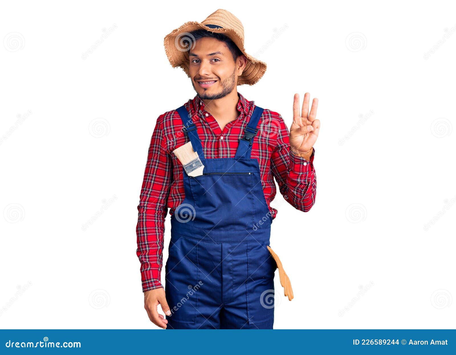 handsome latin american young man weaing handyman uniform showing and pointing up with fingers number three while smiling