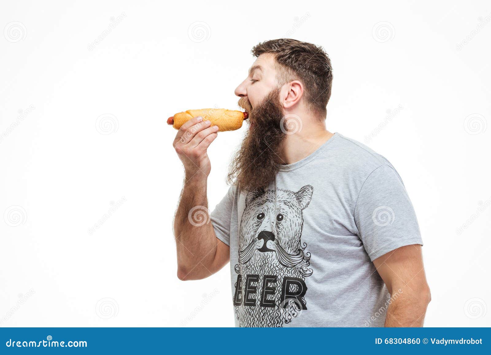 handsome man with beard standing and eating hot dog