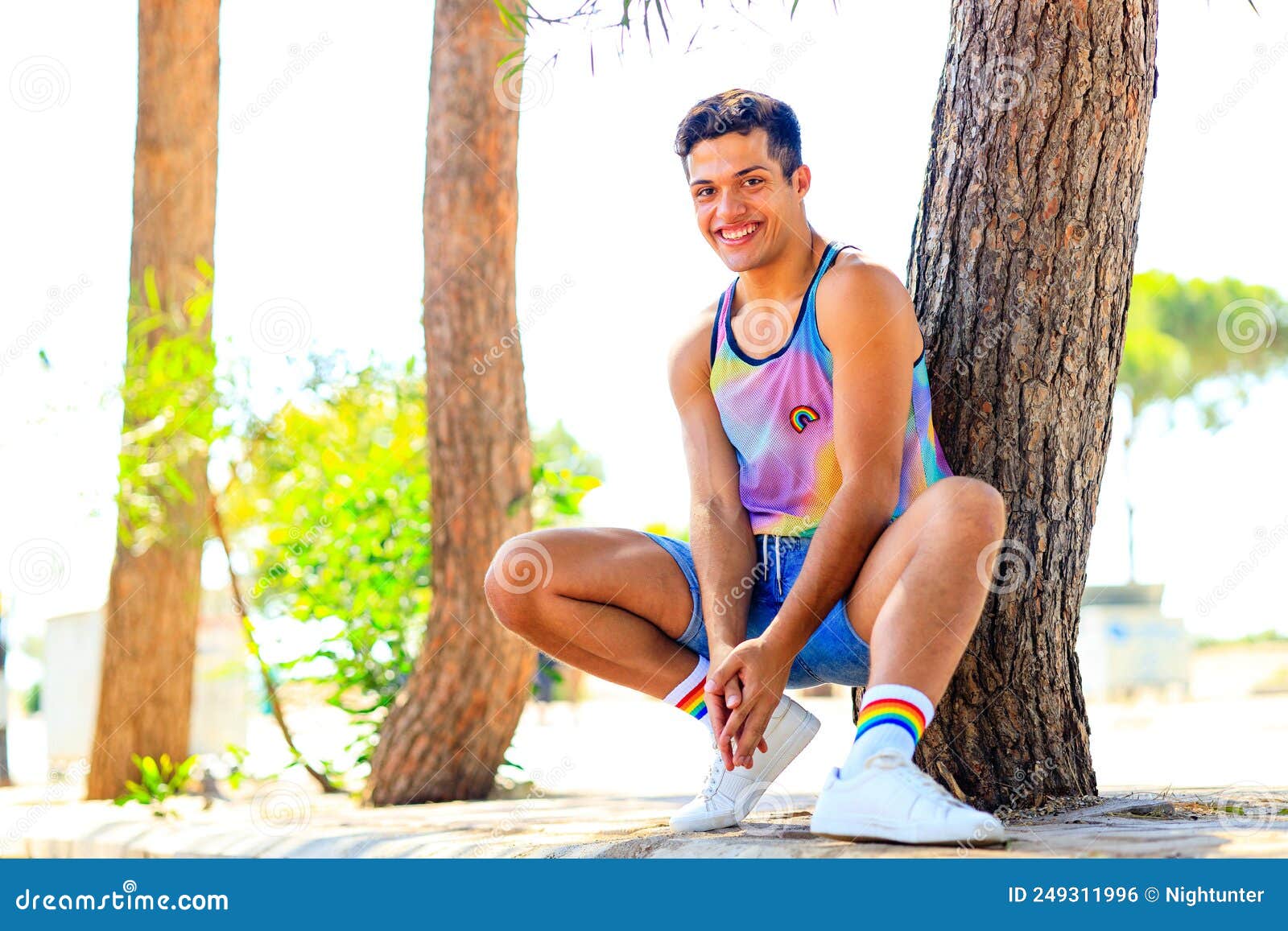 handsome man in colorful shirt with rainbow white socks and choes looking at camera and smile in park