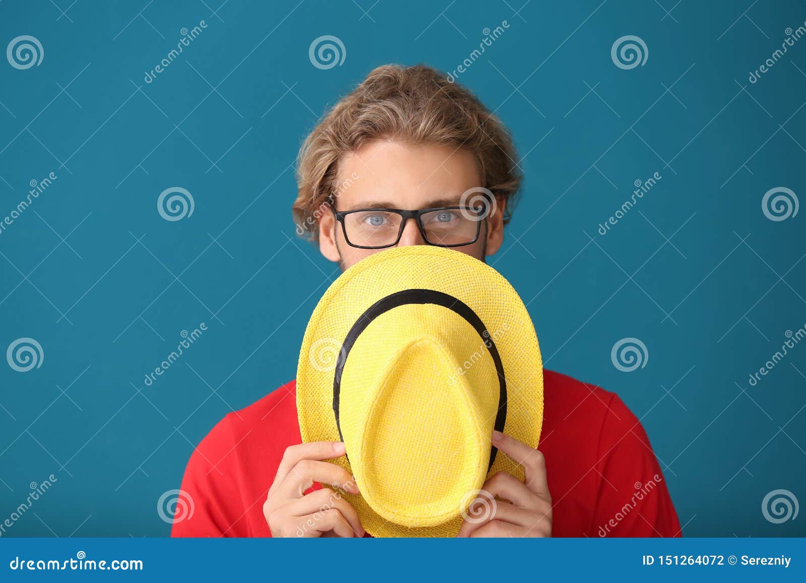 Handsome Man Covering Face with Hat on Color Background Stock Photo ...