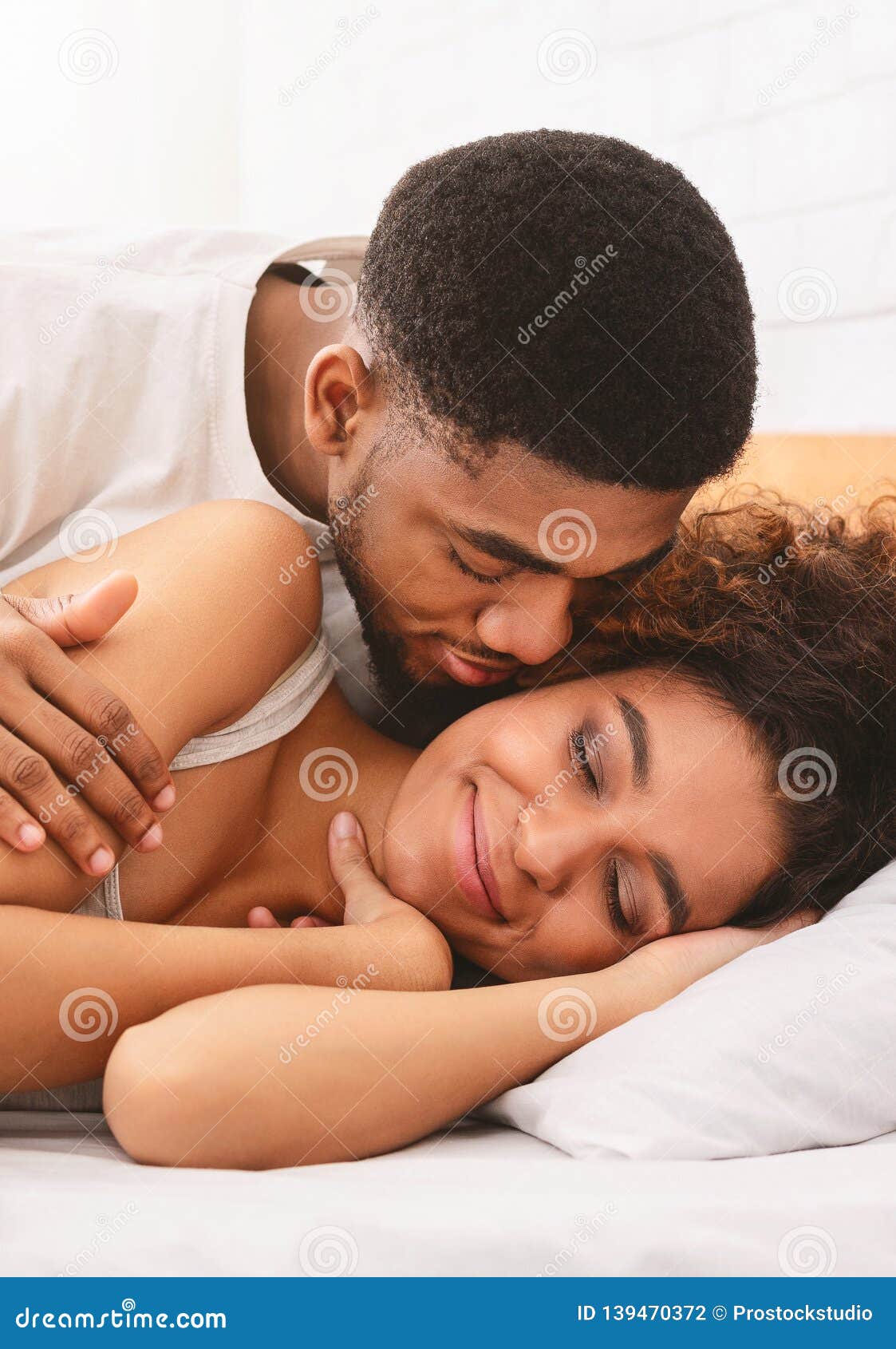 Handsome Man Kissing Woman on Cheek Under in Bed Stock Photo image