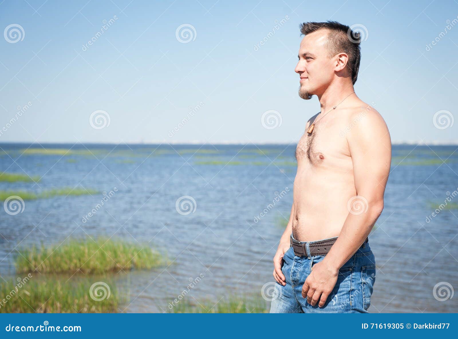 Handsome man with naked torso standing in the sea outdoor