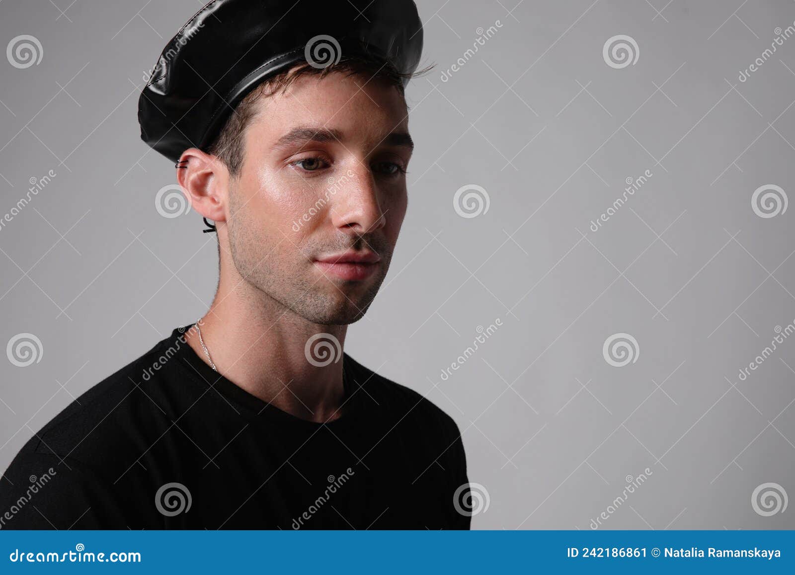 handsome man with serious face expression wears black hat over white background.