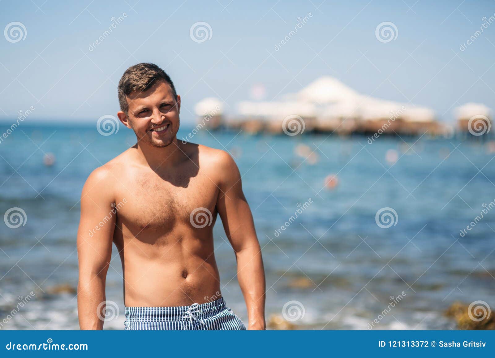 Handsome Man in Shorts Sitting on the Sand Beach Near Rocks on the ...