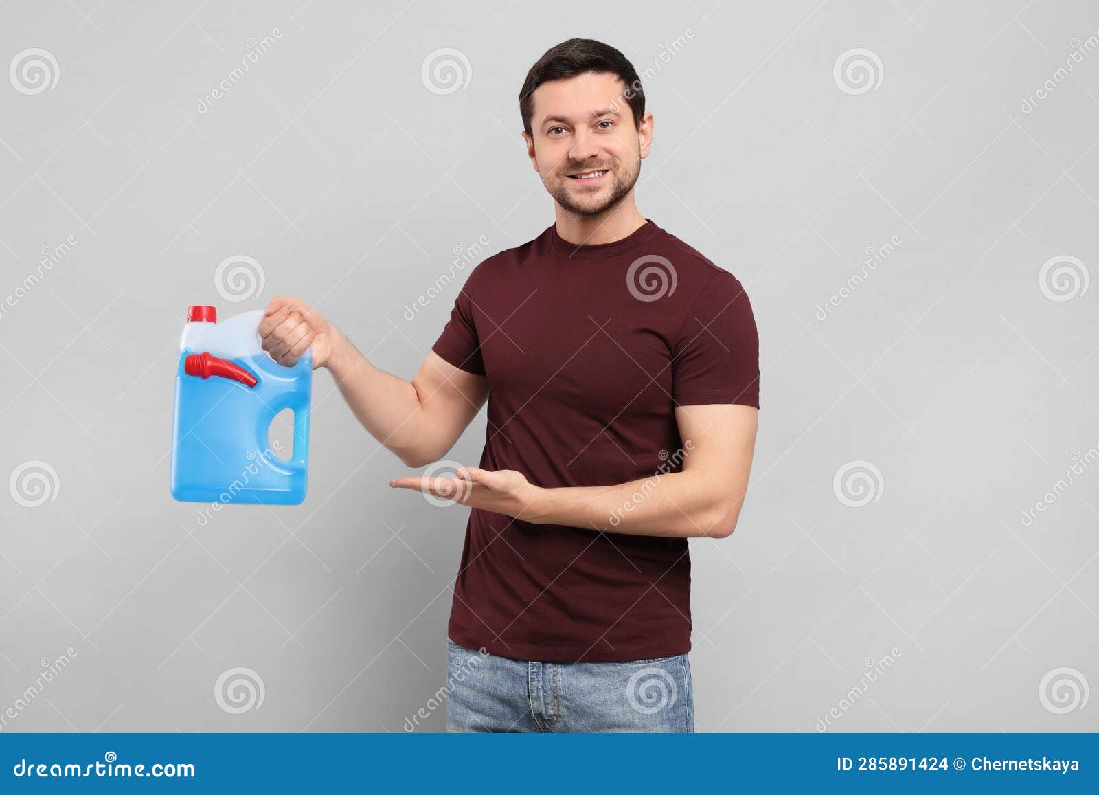 Handsome Man Showing Canister with Blue Liquid on Light Grey Background