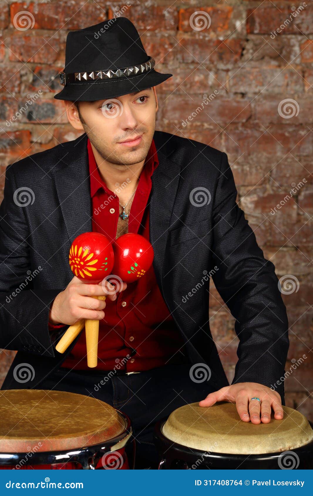 handsome man in suit and hat poses with maracas