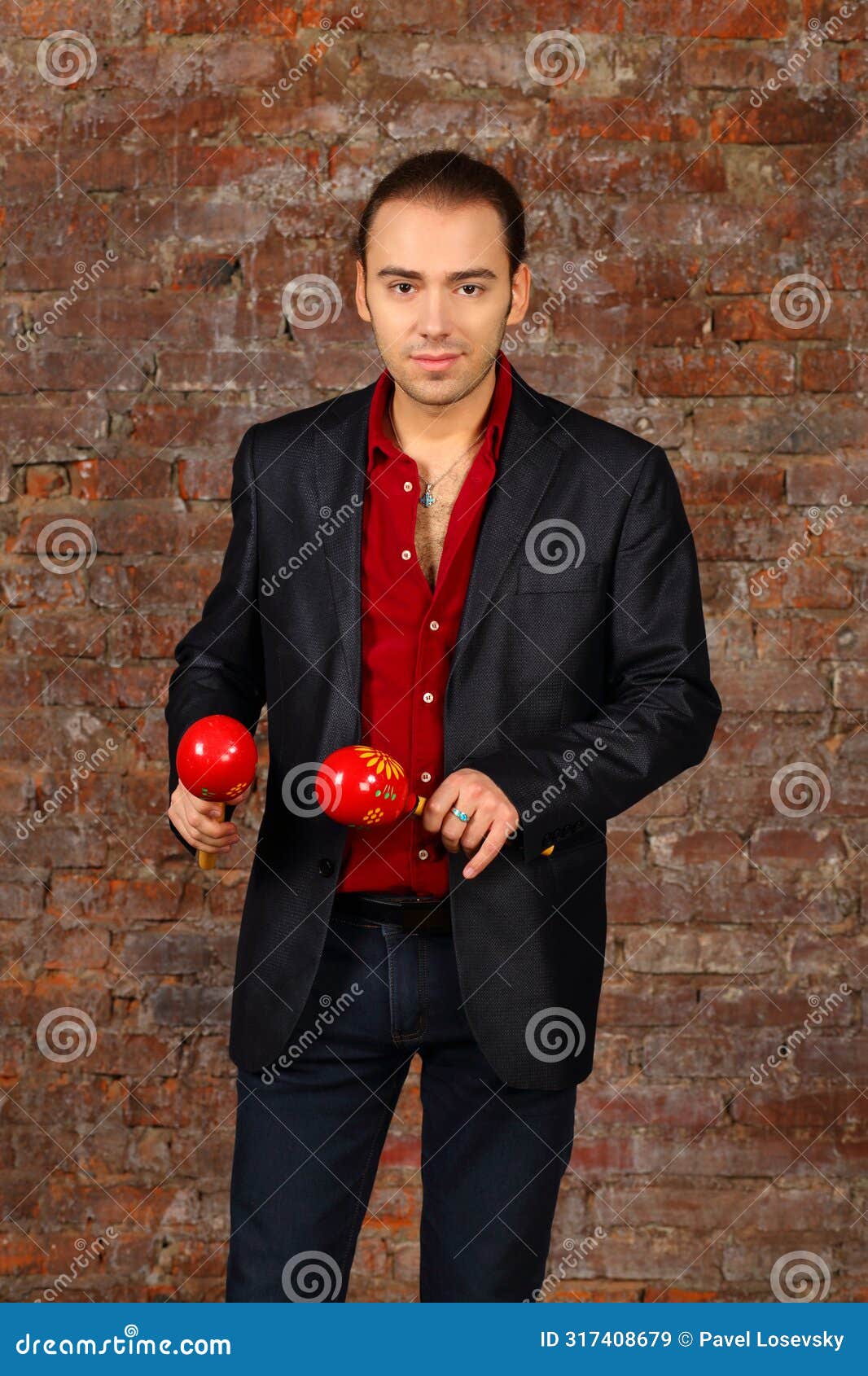 handsome man in suit stands with red maracas in